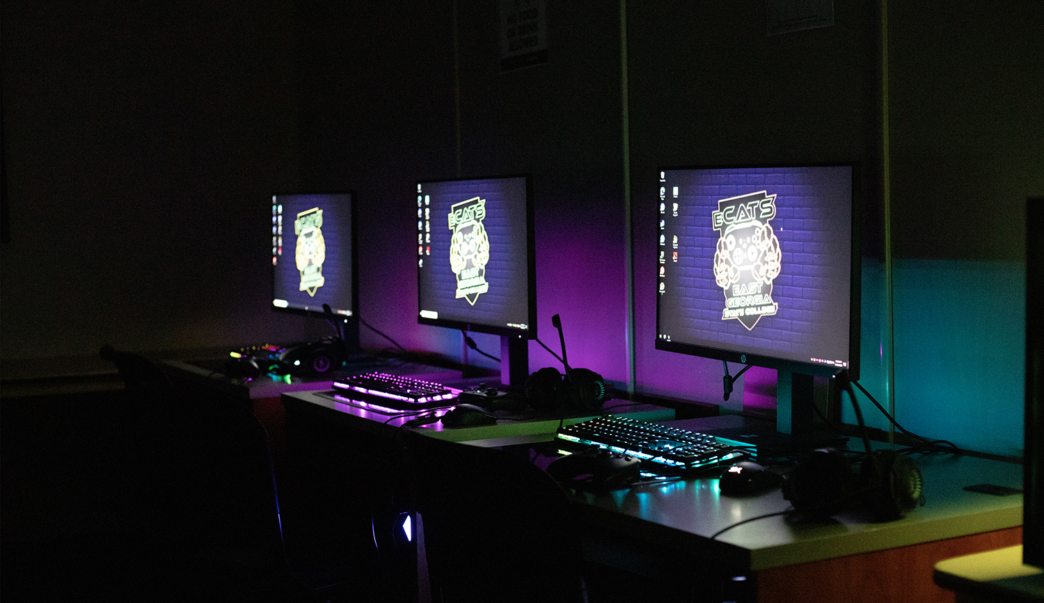 three desktop computer screens and backlit keyboards